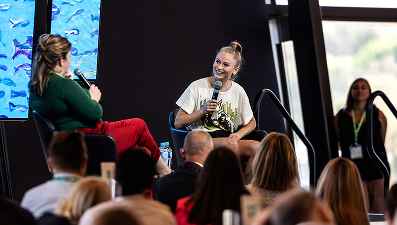 Conference stage with two women sitting, talking to each other